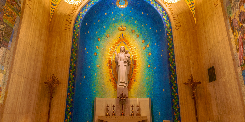 A statue of Mary with blue mosaic behind it