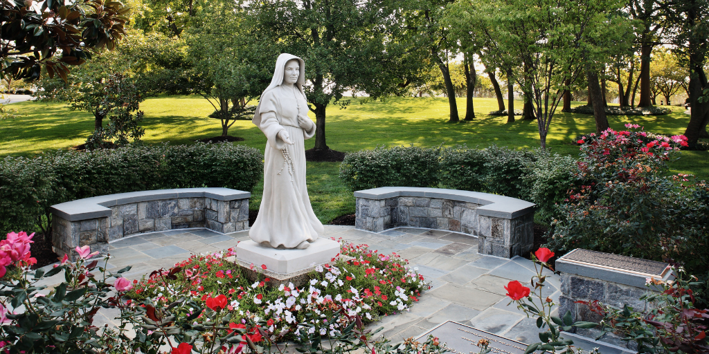 A statue of Mother Theodore Guerrin in Mary's Garden is surrounded by flowers