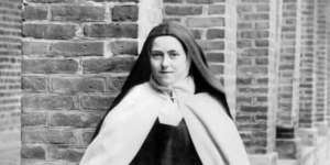 Thérèse of Lisieux wears a habit in front of a brick wall