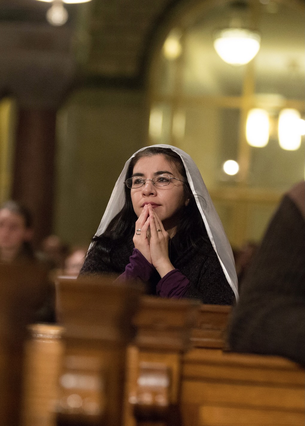 Woman with head-covering prays during Mass in the Crypt Church