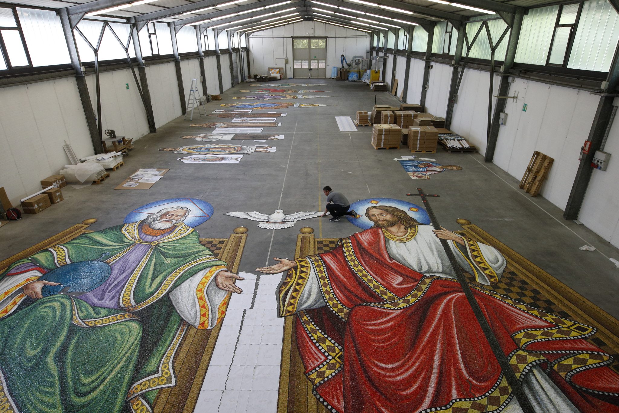 artisan assembles Holy Father and Jesus figures in warehouse in Italy